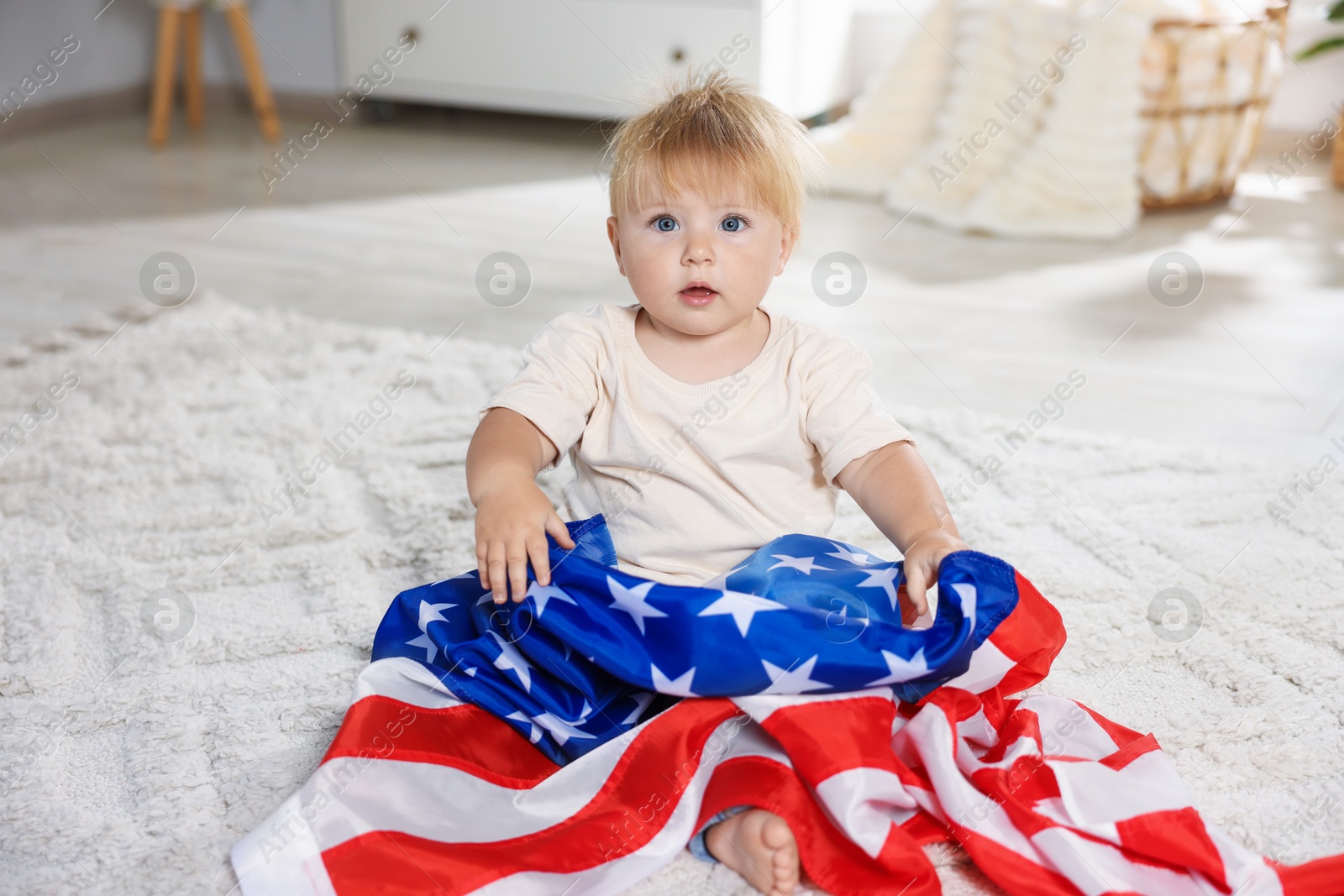Photo of Cute little child with flag of USA on floor at home
