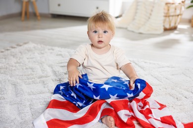 Photo of Cute little child with flag of USA on floor at home