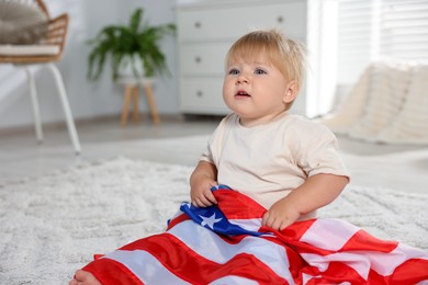 Photo of Cute little child with flag of USA on floor at home, space for text