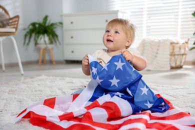 Photo of Cute little child with flag of USA on floor at home, space for text