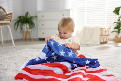Photo of Cute little child with flag of USA on floor at home