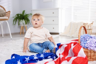 Photo of Cute little child with flag of USA and wicker basket of hydrangea flowers on floor at home