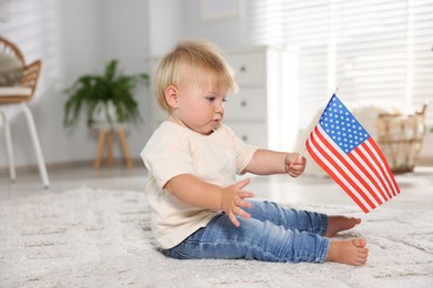 Photo of Cute little child with flag of USA on floor at home
