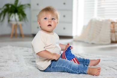 Photo of Cute little child with flag of USA on floor at home