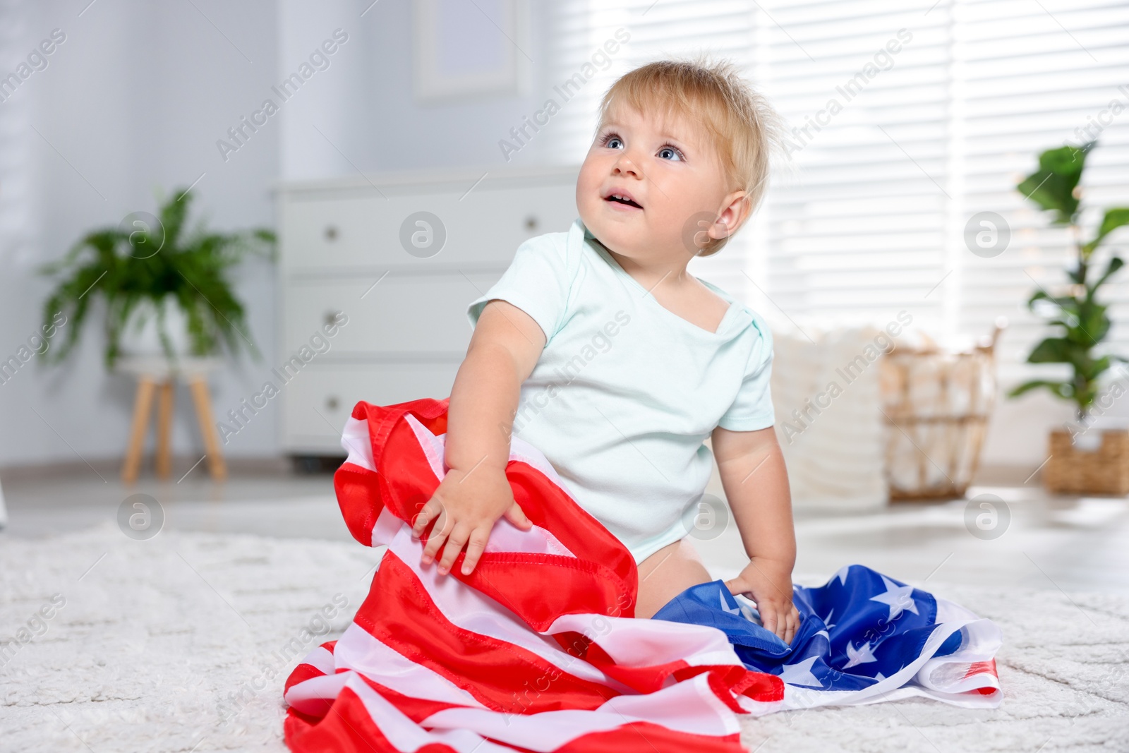 Photo of Cute little child with flag of USA on floor at home