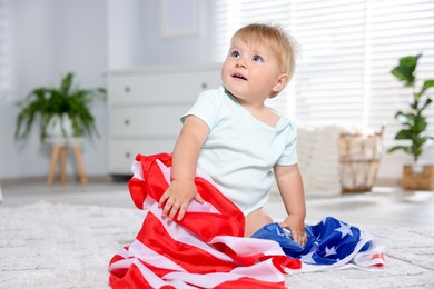Photo of Cute little child with flag of USA on floor at home