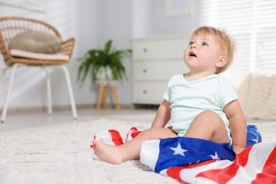 Photo of Cute little child with flag of USA on floor at home, space for text