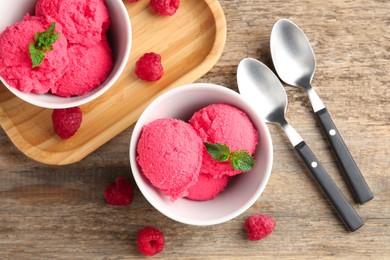 Photo of Delicious raspberry sorbet with mint in bowls, spoons and fresh berries on wooden table, flat lay