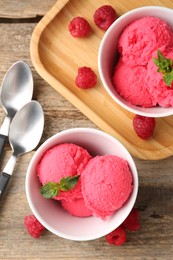 Photo of Delicious raspberry sorbet with mint in bowls, spoons and fresh berries on wooden table, flat lay