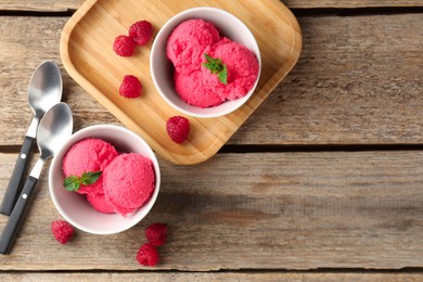 Photo of Delicious raspberry sorbet with mint in bowls, spoons and fresh berries on wooden table, flat lay. Space for text