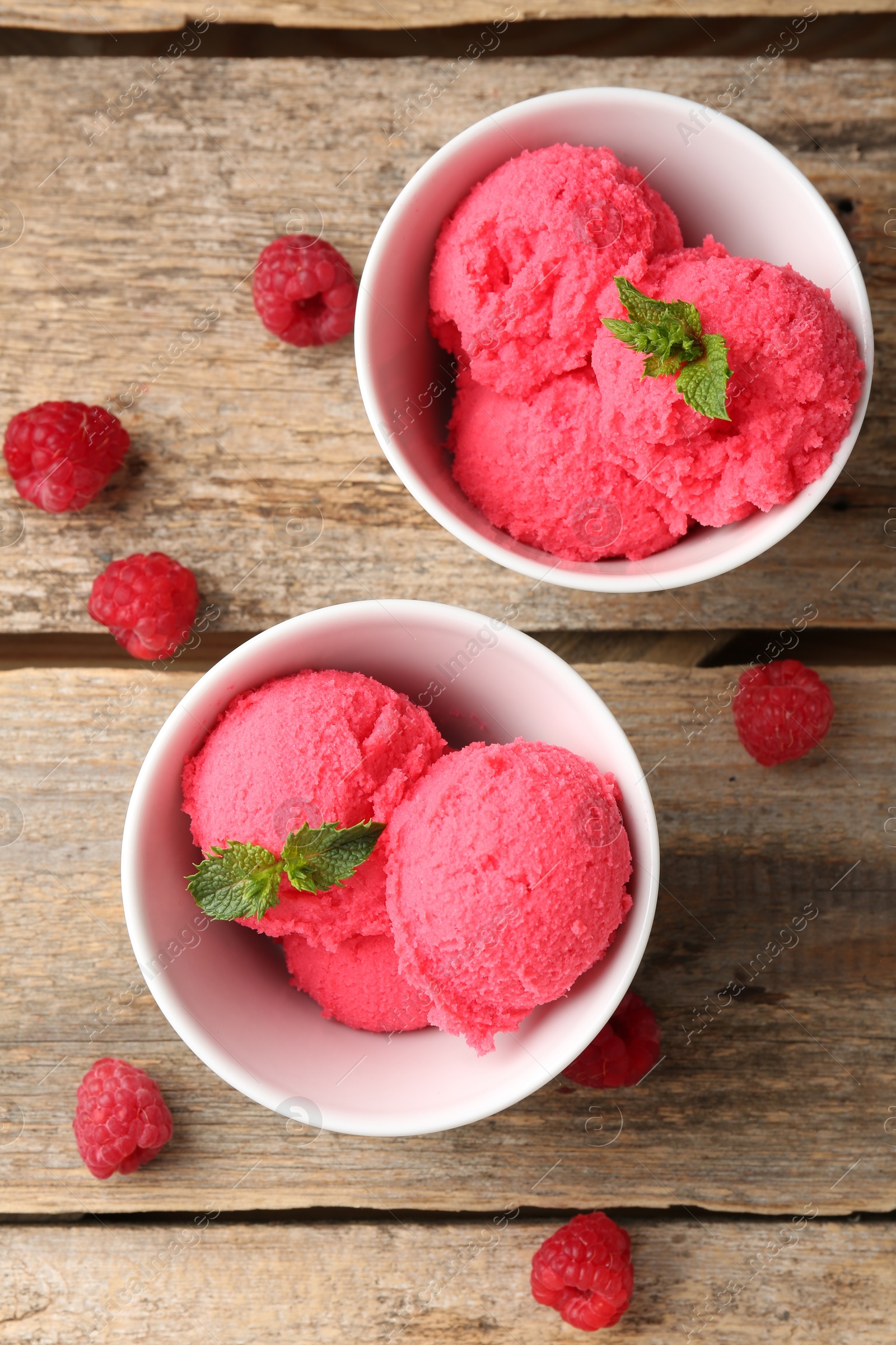 Photo of Delicious raspberry sorbet with mint in bowls and fresh berries on wooden table, flat lay