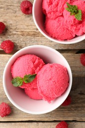 Photo of Delicious raspberry sorbet with mint in bowls and fresh berries on wooden table, flat lay
