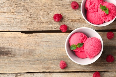 Photo of Delicious raspberry sorbet with mint in bowls and fresh berries on wooden table, flat lay. Space for text