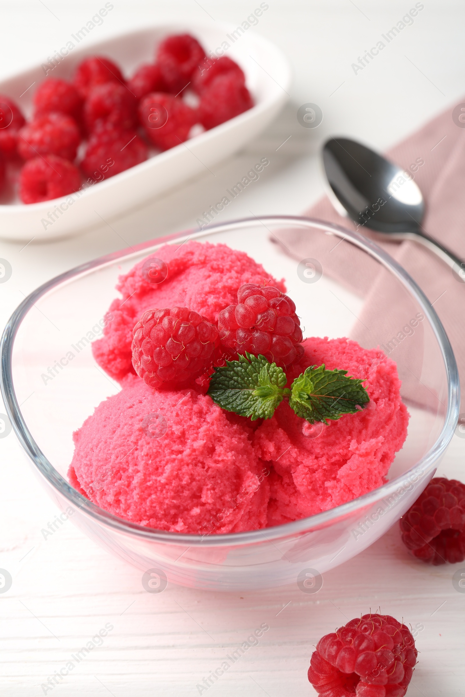 Photo of Delicious raspberry sorbet with mint in bowl and fresh berries on white wooden table, closeup