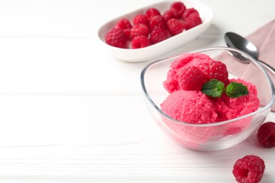 Photo of Delicious raspberry sorbet with mint in bowl and fresh berries on white wooden table, closeup. Space for text