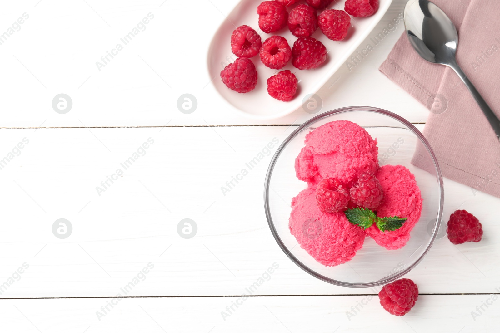 Photo of Delicious raspberry sorbet with mint in bowl, spoon and fresh berries on white wooden table, flat lay. Space for text