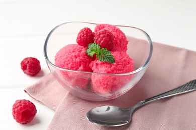 Photo of Delicious raspberry sorbet with mint in bowl, spoon and fresh berries on white wooden table, closeup