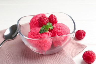 Photo of Delicious raspberry sorbet with mint in bowl, spoon and fresh berries on white wooden table, closeup