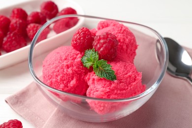Photo of Delicious raspberry sorbet with mint in bowl, napkin and fresh berries on white table, closeup