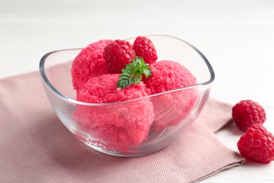 Photo of Delicious raspberry sorbet with mint in bowl, napkin and fresh berries on white wooden table, closeup