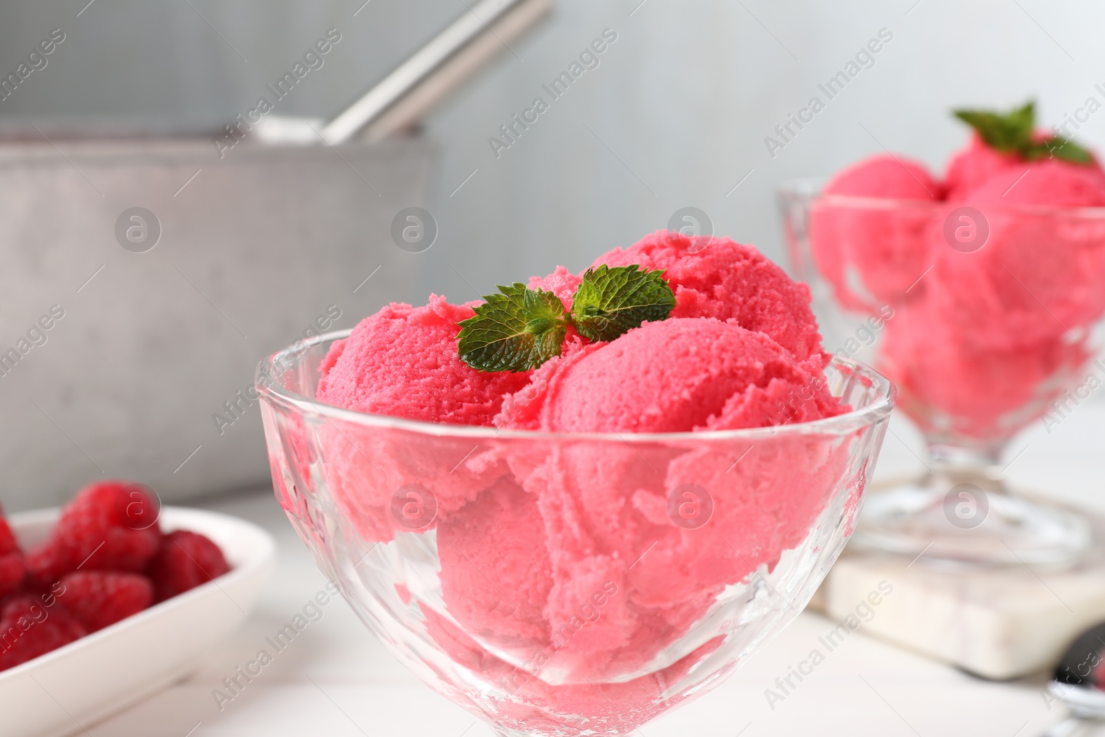 Photo of Delicious raspberry sorbet with mint in dessert bowl on white table against light grey background, closeup