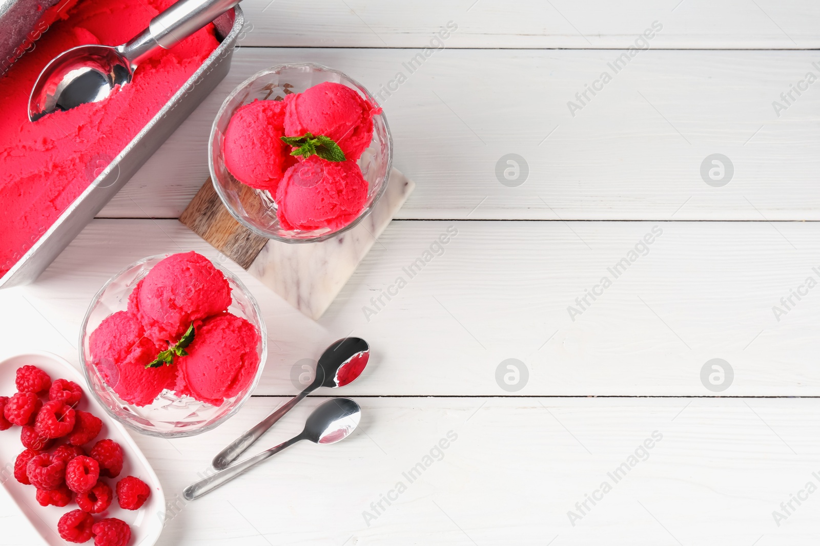 Photo of Delicious raspberry sorbet with mint and fresh berries served on white wooden table, flat lay. Space for text
