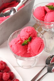Photo of Delicious raspberry sorbet with mint in dessert bowls, spoons and fresh berries on white wooden table, closeup