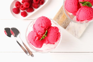 Photo of Delicious raspberry sorbet with mint in dessert bowls, spoons and fresh berries on white wooden table, flat lay