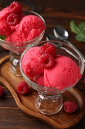 Photo of Delicious raspberry sorbet in dessert bowls, mint and fresh berries on wooden table, closeup
