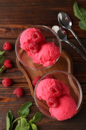 Photo of Delicious raspberry sorbet in dessert bowls, spoons, mint and fresh berries on wooden table, flat lay