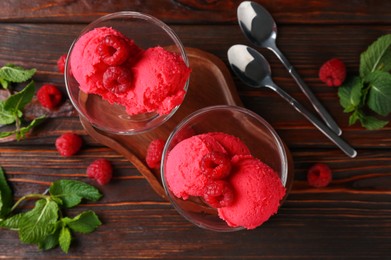 Photo of Delicious raspberry sorbet in dessert bowls, spoons, mint and fresh berries on wooden table, flat lay