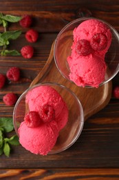 Photo of Delicious raspberry sorbet in dessert bowls, mint and fresh berries on wooden table, flat lay