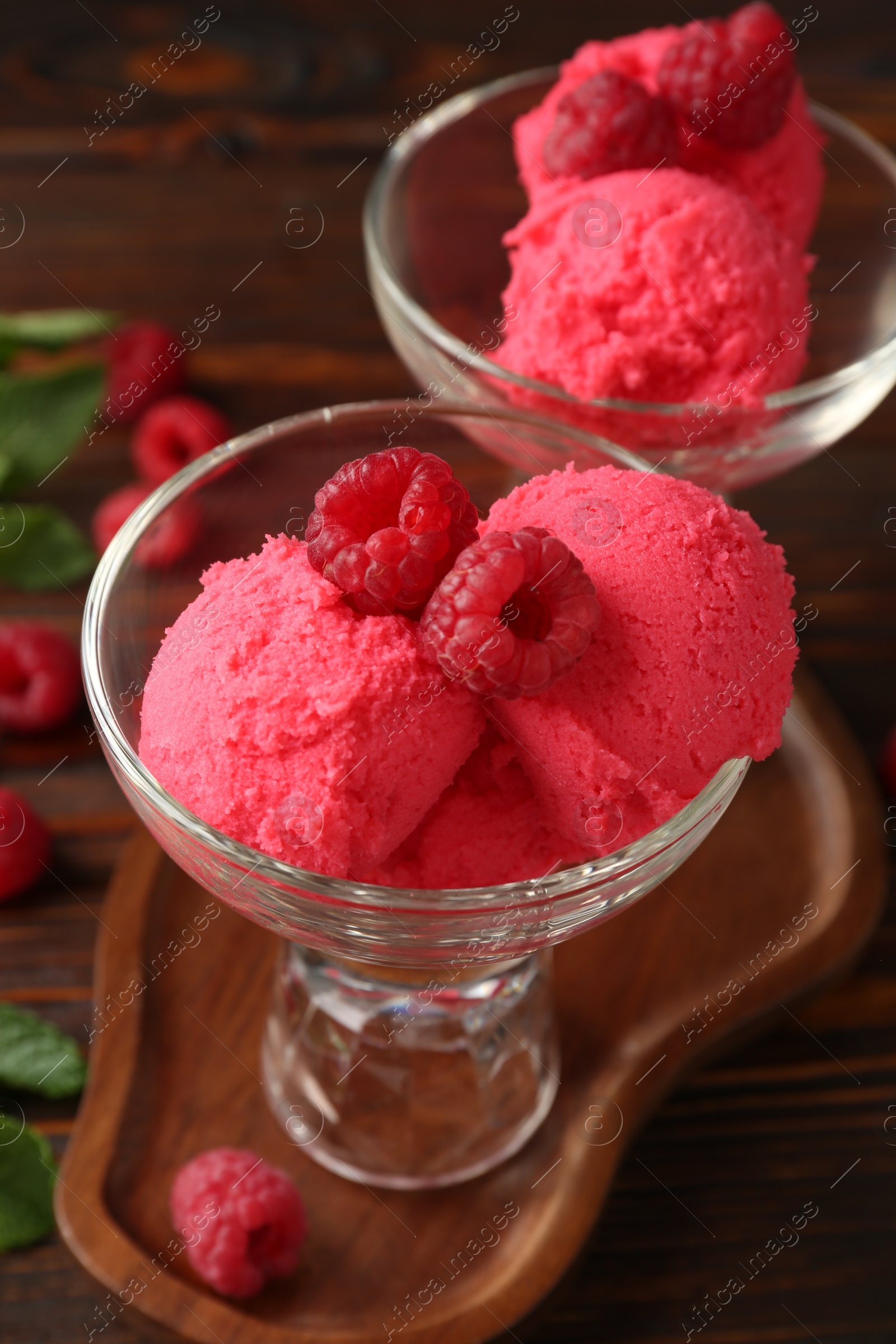 Photo of Delicious raspberry sorbet and fresh berries in dessert bowls on wooden table, closeup