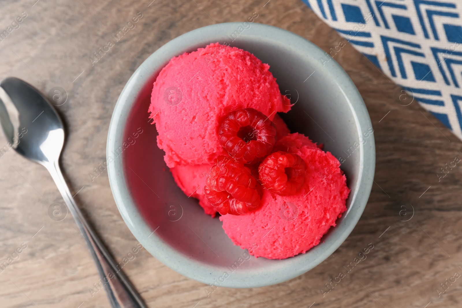 Photo of Delicious raspberry sorbet with fresh berries in bowl and spoon on wooden table, flat lay