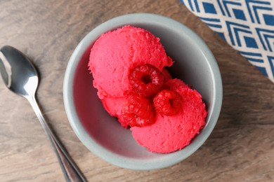 Photo of Delicious raspberry sorbet with fresh berries in bowl and spoon on wooden table, flat lay
