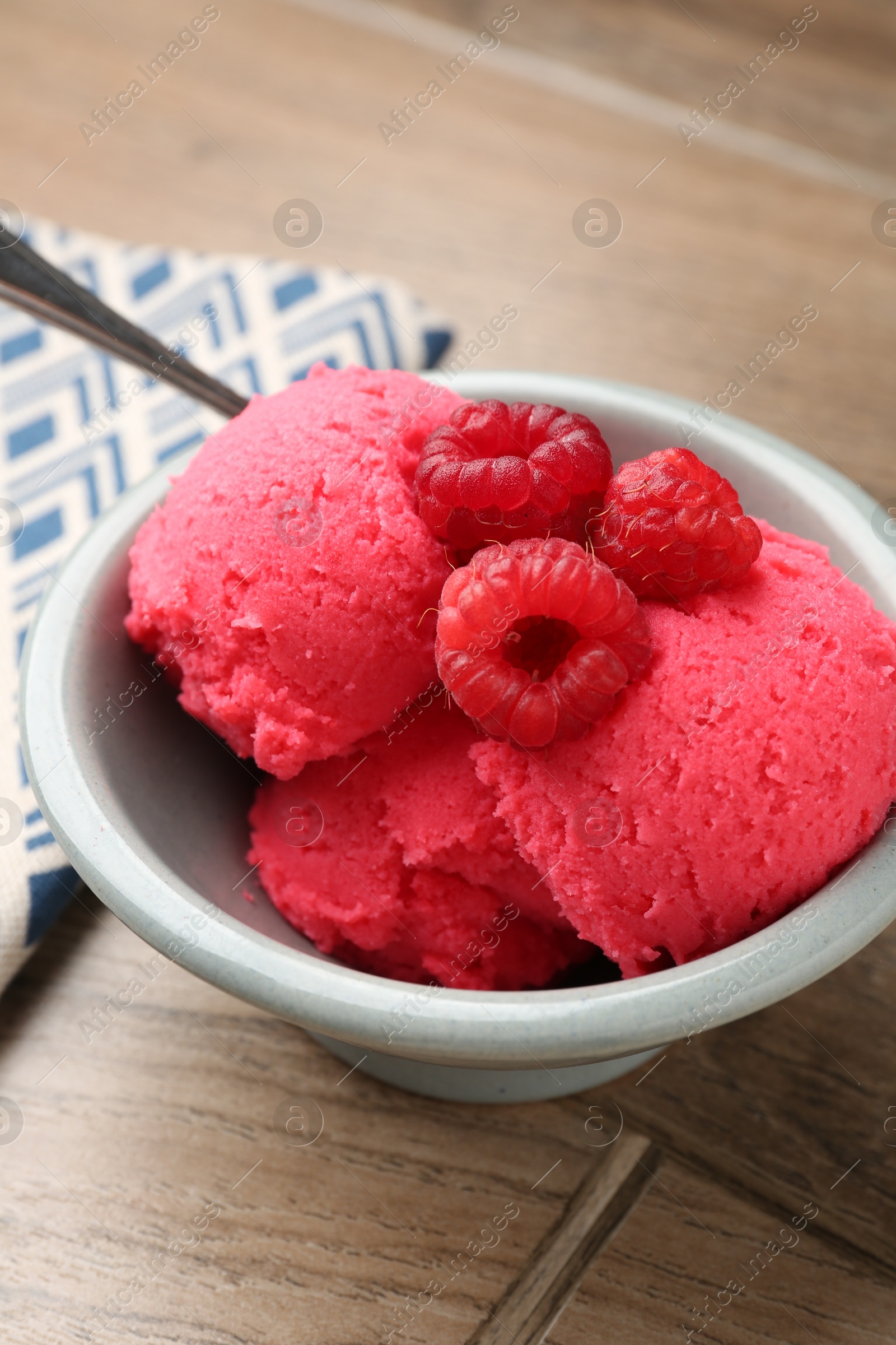 Photo of Delicious raspberry sorbet with fresh berries in bowl on wooden table, closeup