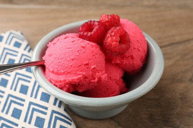 Photo of Delicious raspberry sorbet with fresh berries in bowl on wooden table, closeup