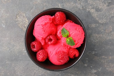 Photo of Delicious raspberry sorbet with fresh berries and mint in bowl on grey textured table, top view