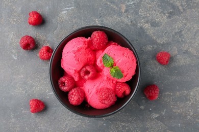 Photo of Delicious raspberry sorbet with fresh berries and mint in bowl on grey textured table, flat lay