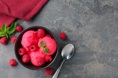Photo of Delicious raspberry sorbet with fresh berries and mint in bowl served on grey textured table, flat lay. Space for text