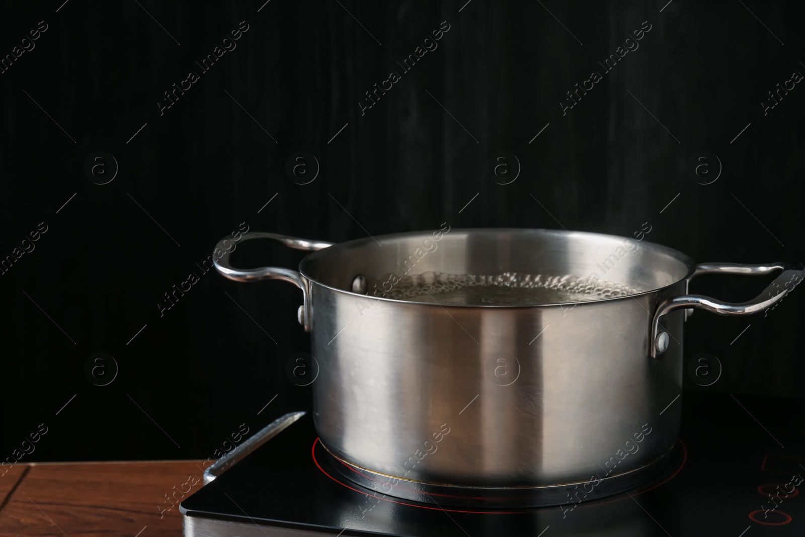 Photo of Metal pot with boiling water on stove in kitchen