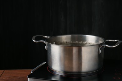 Photo of Metal pot with boiling water on stove in kitchen