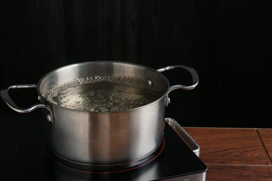 Photo of Metal pot with boiling water on stove in kitchen