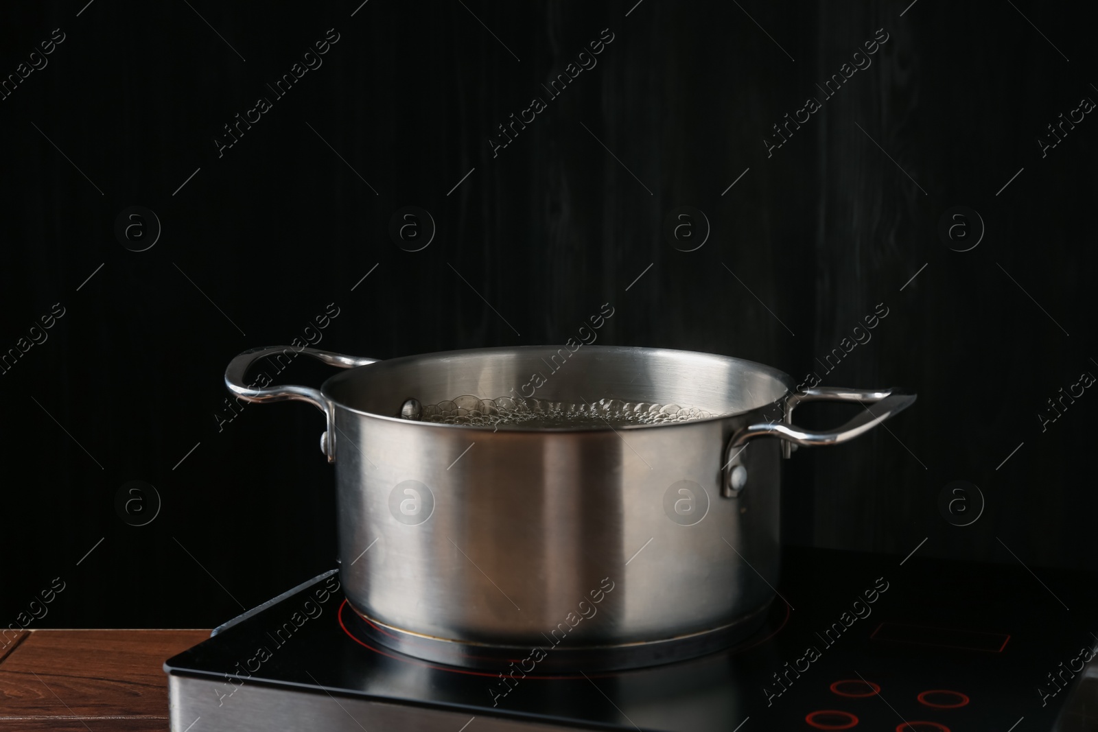 Photo of Metal pot with boiling water on stove in kitchen