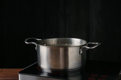 Photo of Metal pot with boiling water on stove in kitchen