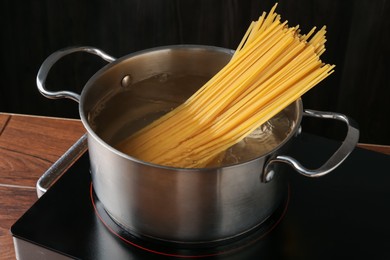Photo of Fresh tagliatelle pasta boiling in pot with water on electric stove, closeup