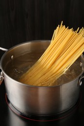 Photo of Fresh tagliatelle pasta boiling in pot with water on electric stove, closeup