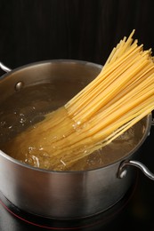Photo of Fresh tagliatelle pasta boiling in pot with water on electric stove, closeup
