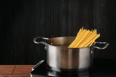 Photo of Fresh tagliatelle pasta boiling in pot with water on electric stove