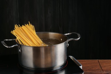 Photo of Fresh tagliatelle pasta boiling in pot with water on electric stove